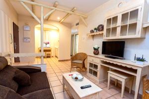ein Wohnzimmer mit einem Sofa und einem TV in der Unterkunft Apartahotel La Espadaña in Rota