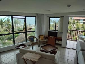 ein Wohnzimmer mit einem Sofa, Stühlen und Fenstern in der Unterkunft Marulhos Resort Porto de Galinhas in Porto De Galinhas