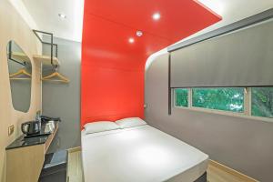 Hotel 81 Lavender في سنغافورة: غرفة صغيرة بها سرير وجدار احمر