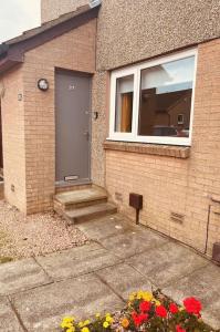 a house with a door and flowers in front of it at Beautiful refurbished, self-contained apartment in Fife