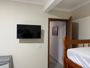 ein Schlafzimmer mit einem Bett und einem Flachbildfernseher an der Wand in der Unterkunft Apartamento Só Alegria in Bombinhas