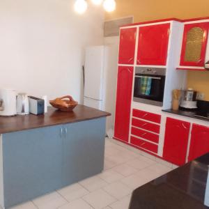 a kitchen with red cabinets and a white refrigerator at Maison de campagne proche des plages in Sainte-Rose