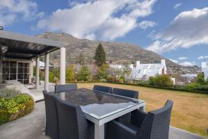 a patio with a table and chairs and a mountain at Lakeside Indulgence on Wilmot in Queenstown
