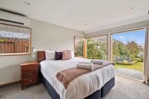 ein Schlafzimmer mit einem großen Bett und einem Fenster in der Unterkunft Lakeside Indulgence on Wilmot in Queenstown