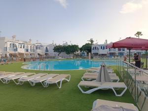 a group of lounge chairs and a swimming pool at Bungalow Playmar in Playa del Ingles