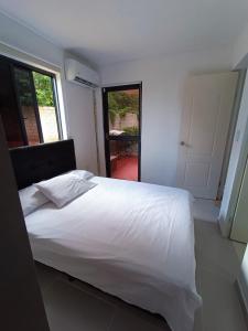 ein Schlafzimmer mit einem weißen Bett und einem großen Fenster in der Unterkunft Apartamento Portal de la Sierra 3 Habitaciones in Santa Marta