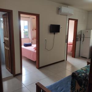 a room with two beds and a room with a tv at Pousada Pegadas na Areia in Palhoça