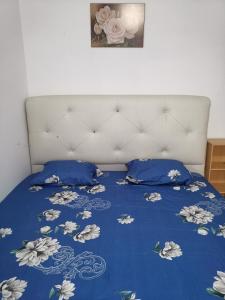 a bed with a blue bedspread with flowers on it at AniS Homestay 2 @ Nilai in Nilai