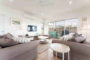 sala de estar con 2 sofás y TV en Boomer Beach Retreat- Pet and Family Friendly, en Port Elliot