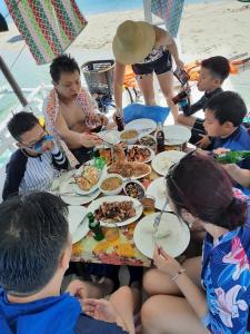 un grupo de personas sentadas alrededor de una mesa comiendo comida en Jao bay boat charter, en Talibon