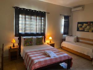 a bedroom with two beds and two lamps and two windows at Chico de Sá Pousada in Pirenópolis