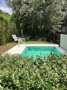a swimming pool with a chair and a table at La Franca Cabaña de Veraneo in Villa General Belgrano