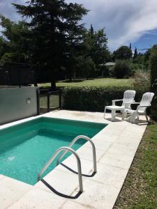 a swimming pool with two white chairs next to it at La Franca Cabaña de Veraneo in Villa General Belgrano
