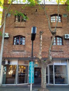 a brick building with a parking meter next to a tree at Hotel Sol Colonia in Colonia del Sacramento