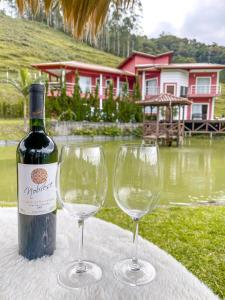 a bottle of wine and two wine glasses on a table at AMPLA CASA DE CAMPO - MORADA DA SERRA in Aguas Mornas