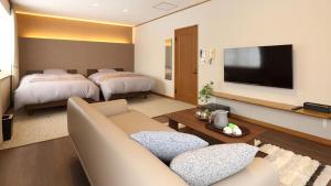 ein Wohnzimmer mit 2 Betten, einem Sofa und einem TV in der Unterkunft Pension Hinode in Hachimantai