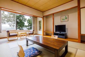 a living room with a wooden table and a tv at KAMENOI HOTEL Itako in Itako