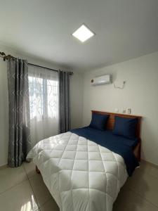 1 dormitorio con 1 cama blanca grande con almohadas azules en Résidence 2JGE en Duala