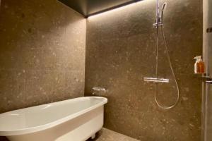 a bathroom with a bath tub and a shower at Kyoto ITOYA Hotel Mon in Kyoto