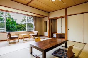 a living room with a table and chairs and a large window at KAMENOI HOTEL Itako in Itako