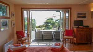 a living room with a door open to a patio at Hokianga Haven in Opononi
