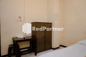 a room with a bed and a table and a locker at Sawojajar Inn Mitra RedDoorz in Malang