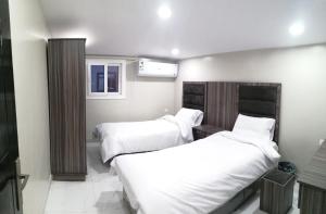 two beds in a hotel room with white sheets at Sharm Beach Suites Private hotel apartments in Yanbu