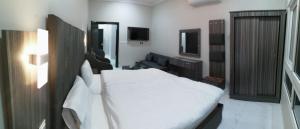 a bedroom with a white bed and a television at Sharm Beach Suites Private hotel apartments in Yanbu
