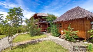 Moalboal Eco Lodge في موالبوال: منزل به سقف من القش وساحة