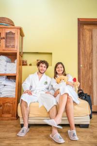a man and woman sitting on a bed with a teddy bear at El Jardin Lodge & Spa in Puerto Misahuallí