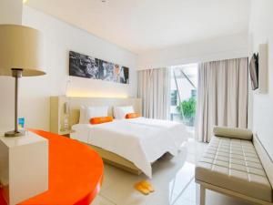 una camera d'albergo con letto e sedia di HARRIS Hotel and Conventions Denpasar Bali a Denpasar