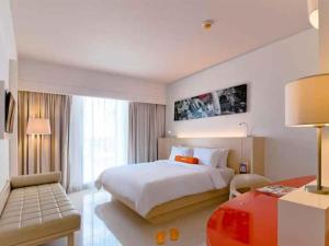 una camera d'albergo con letto e scrivania di HARRIS Hotel and Conventions Denpasar Bali a Denpasar