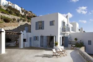 a large white building with chairs in a courtyard at Elegance Villa in Platis Gialos