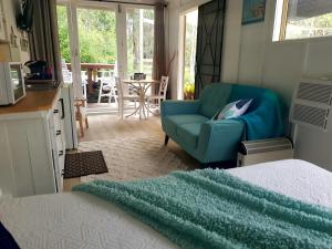 uma sala de estar com um sofá azul e uma cadeira em Forest view bungalow em Nambucca Heads