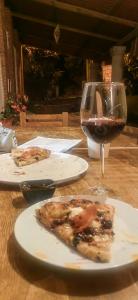 瓦薩德奧坎波的住宿－CABAÑAS LOS LAURELES，一张桌子,上面放着一片比萨饼和一杯葡萄酒