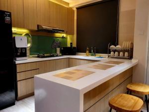 a kitchen with a white counter and wooden cabinets at Executive Premium Comfy Home Mount Austin JB 5Pax in Johor Bahru
