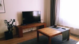ein Wohnzimmer mit einem TV und einem Couchtisch in der Unterkunft Downtown Apartment Rentals in Šiauliai