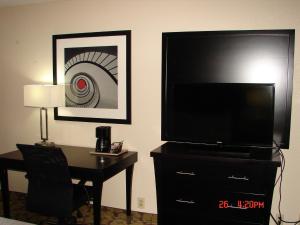 a bedroom with a desk and a large flat screen tv at Ramada Plaza by Wyndham Charlotte South End Airport in Charlotte