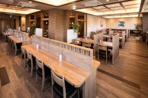 a dining room with wooden tables and chairs at Hotel Route Inn Shikoku Chuo in Shikokuchuo