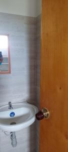 ein Badezimmer mit einem weißen Waschbecken und einer Holztür in der Unterkunft Apartamento Santa Marta Piscina cerca del Rodadero in Santa Marta