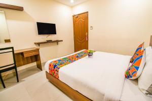 Dormitorio con cama, escritorio y TV en FabHotel Thejas Paaradise Coimbatore International Airport, en Coimbatore