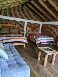 ウアスカ・デ・オカンポにあるCABAÑAS LOS LAURELESのベッド2台、ベンチが備わるレンガの壁の客室です。