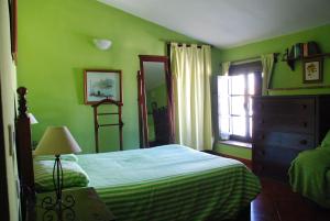 a green bedroom with a bed and a window at Posada La Casa Grande in Jimena de la Frontera