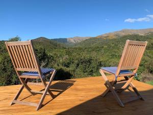 two chairs sitting on a deck with mountains in the background at Studholme Glamping in Hunter