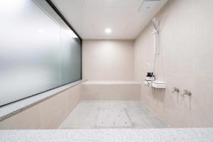 y baño blanco con bañera y ducha. en Ytt Hotel en Busan