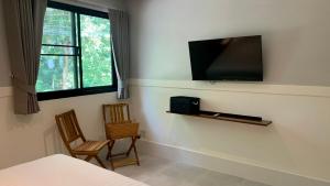 a bedroom with a tv on the wall and two chairs at Island House Rentals 25 in Ko Samed
