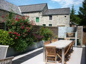 eine Terrasse mit einem Holztisch, Stühlen und Blumen in der Unterkunft La Grange de David is accessible to people with reduced mobility 