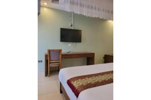 - une chambre avec un lit et une télévision murale dans l'établissement Acholi Inn, à Gulu