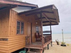ein Holzhaus am Strand mit einer Veranda in der Unterkunft Pinks Bungalow in Baan Tai