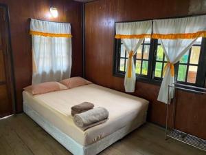a bedroom with a bed with two towels on it at Pinks Bungalow in Baan Tai